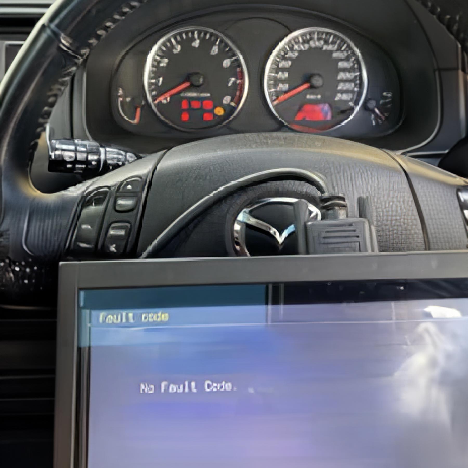 Closeup of diagnostics screen in front of car steering wheel and dashboard