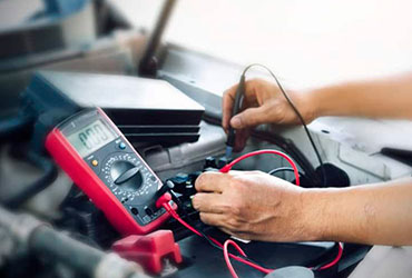 Closeup of mechanic using a multimeter to test a car engine component